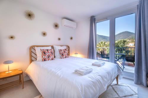 une chambre avec un grand lit et une grande fenêtre dans l'établissement Petite maison pour 6 - jardin clim piscine parking, à Théoule-sur-Mer