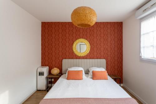 a bedroom with a large white bed with orange pillows at Happy Stay Disney Two - Apartment with garden & parking in Montévrain