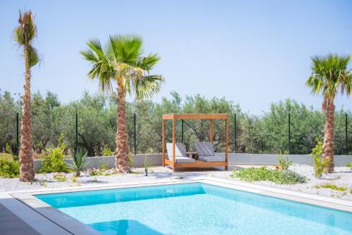 - une piscine avec un kiosque et des palmiers dans l'établissement Aetheria & Aura Suites by Temma Villas, à Chersónissos