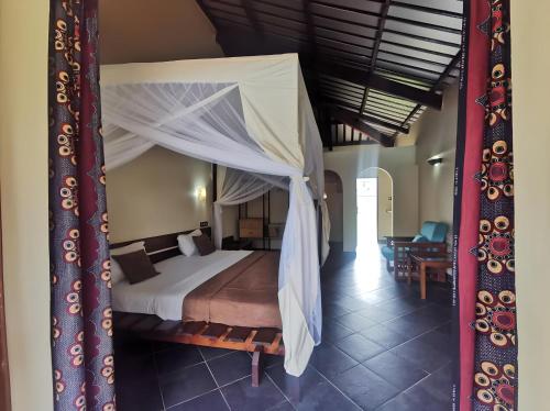 a bedroom with a bed with a canopy at Hôtel de la Palmeraie in Bujumbura