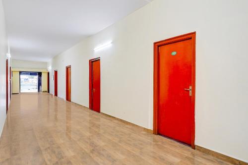 an empty hallway with red doors and wooden floors at Super Hotel O Poigai Near Airport in Vellore