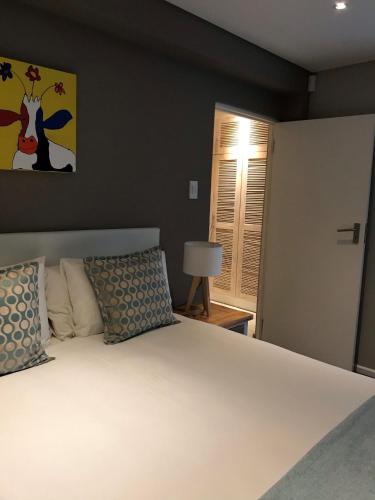 a bedroom with a white bed and a lamp at Bloemenzee Boutique B&B in Gordonʼs Bay