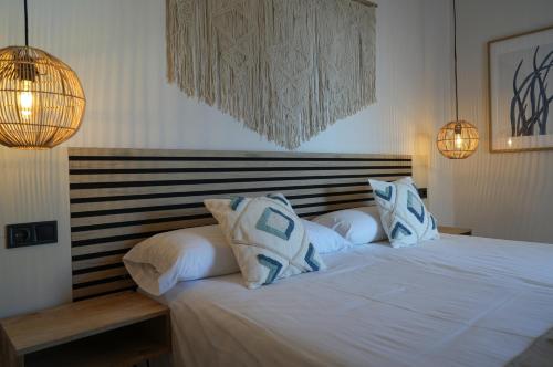 a bedroom with a white bed with blue and white pillows at Apartamentos Ses Veles in Cala Llonga