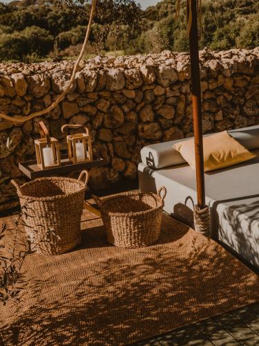two baskets sitting on a table next to a stone wall at Amagatay Luxury Boutique Hotel - Adults Only in Alaior