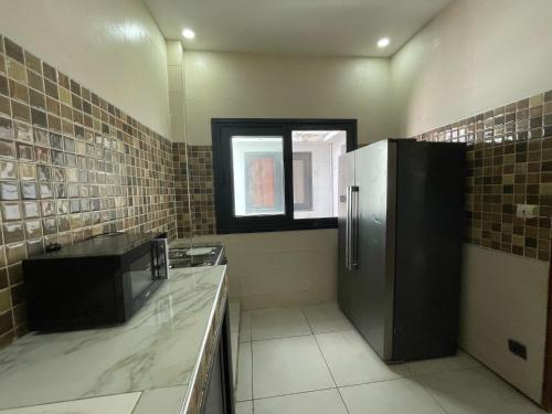 a kitchen with a refrigerator and a window at Koivogui in Dakan