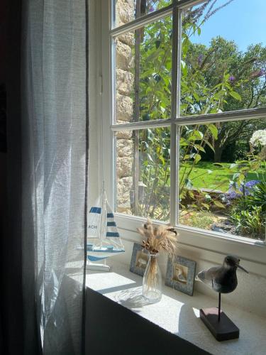une fenêtre avec un bateau dans un vase sur un rebord de fenêtre dans l'établissement Fleur de Sel, longère au calme , proche mer et plages, à Assérac