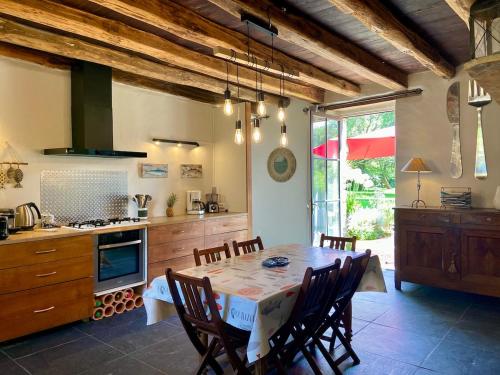 une cuisine avec une table et des chaises dans une pièce dans l'établissement Fleur de Sel, longère au calme , proche mer et plages, à Assérac