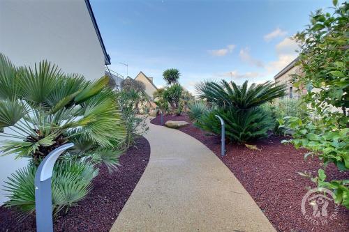 a walkway through a garden with palm trees and plants at Le spa de la palmeraie in Penvénan