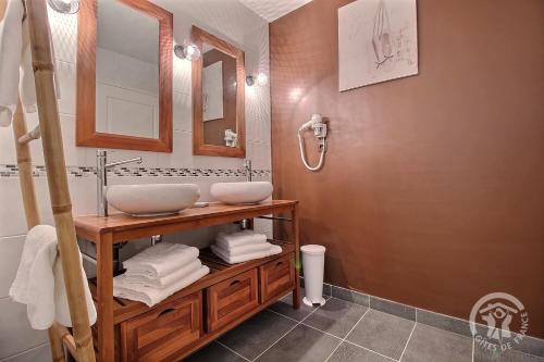 a bathroom with two sinks on a wooden vanity at Le spa de la palmeraie in Penvénan