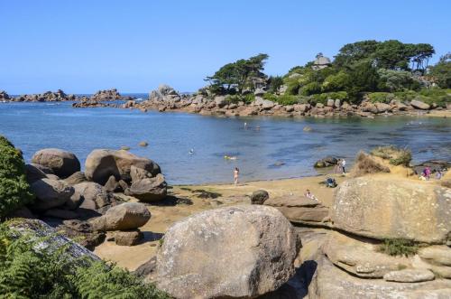 a beach with rocks and people swimming in the water at Le spa de la palmeraie in Penvénan