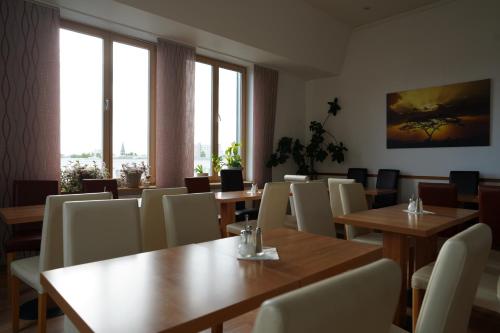 een restaurant met houten tafels en stoelen en ramen bij Hotel Ambert in Berlijn