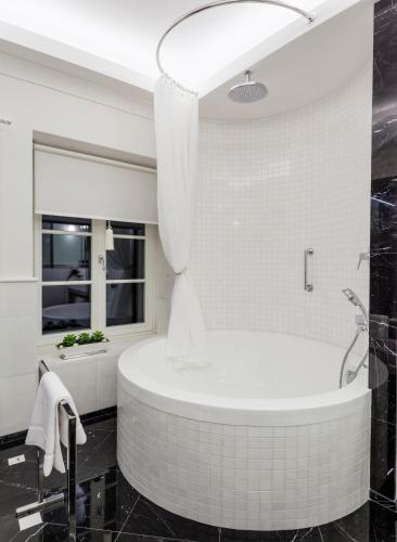 a white bathroom with a tub and a window at Hotel Bellotto in Warsaw