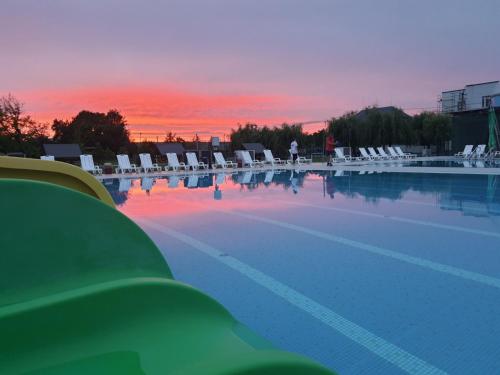 a large swimming pool with chairs and a sunset at Tulipan Hotel Aquapark in Vyshkove