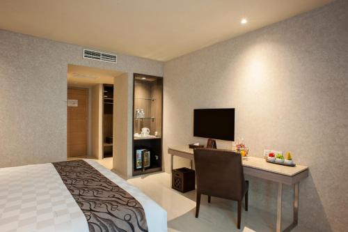 a bedroom with a bed and a desk with a television at Aria Centra Surabaya in Surabaya