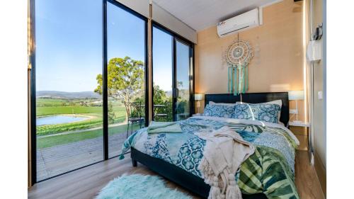 a bedroom with a bed and a large window at A Dam Good View by Tiny Away in Dixons Creek