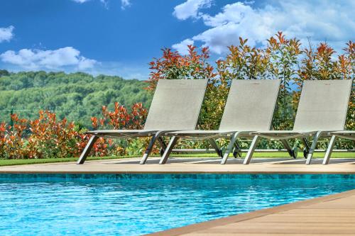 3 chaises assises à côté d'une piscine dans l'établissement Villa Jylloue Modern 6 chambres , 2 minutes from royal golf club, à Mougins