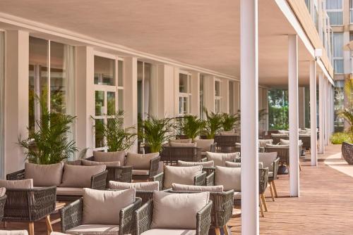 an outdoor patio with chairs and tables on a building at Zafiro Alzinar Mar Adults Only - Refurbished 2025 in Can Picafort