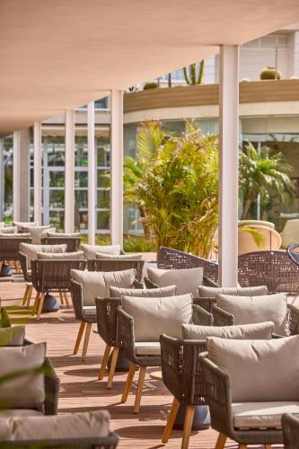a row of chairs and tables on a patio at Zafiro Alzinar Mar Adults Only - Refurbished 2025 in Can Picafort
