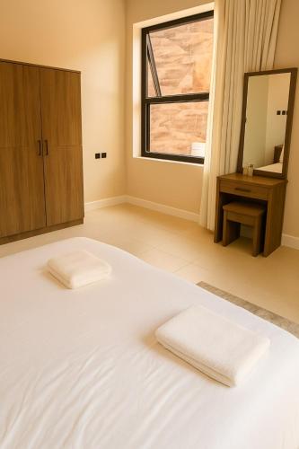 a large white bed with two white towels on it at جونيور بإطلالة على الجبل in AlUla