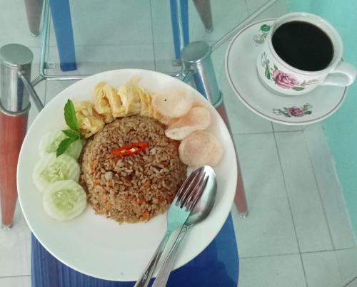 a plate of food with rice and a cup of coffee at Petra Homestay Bangka Leda in Ruteng