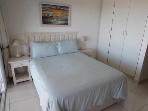 a bedroom with a white bed with blue pillows at 5 Manaba Breeze, Uvongo in Margate