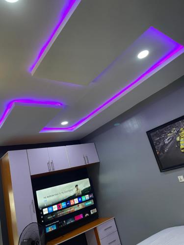 a room with a tv and purple lights on the ceiling at Umbrella Properties hotels and apartments - Moniya in Ibadan
