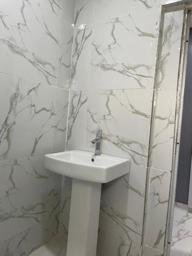 a white sink in a bathroom with marble walls at Umbrella Properties hotels and apartments - Moniya in Ibadan