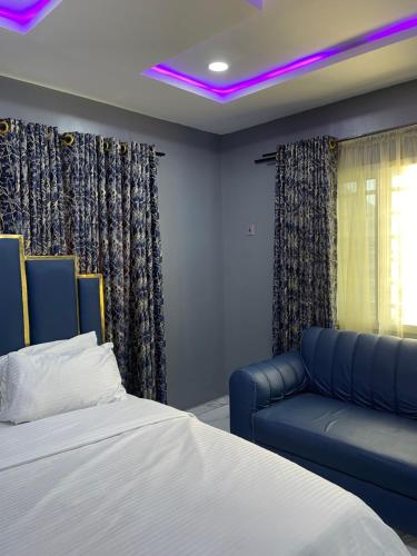 a bedroom with a bed and a blue couch at Umbrella Properties hotels and apartments - Moniya in Ibadan