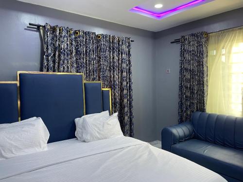 a bedroom with a bed and a blue chair at Umbrella Properties hotels and apartments - Moniya in Ibadan