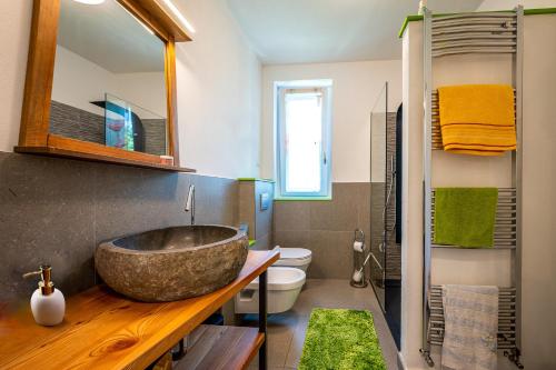 ein Badezimmer mit einem großen Steinwaschbecken und einem WC in der Unterkunft Casa Jacqueline in Dongo