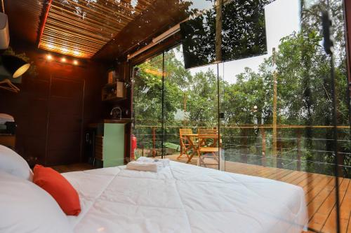 a bedroom with a bed and a large glass window at João de Barro - Deck Tiny House in Mairiporã