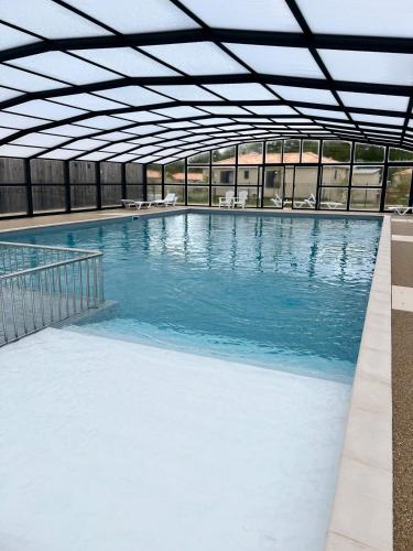 une grande piscine avec de l'eau bleue dans un immeuble dans l'établissement Bungalow à quinze minutes des plages, à Saubrigues