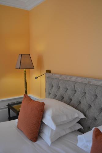 a bedroom with a bed with a gray headboard and a lamp at Hotel Le Saint Paul in Saint-Paul-de-Vence