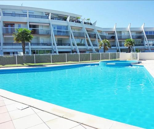 une grande piscine bleue devant un immeuble dans l'établissement Vittoria Immobilier 7 -REGLEMENT SUR PLACE - chèques vacances acceptés, à La Grande Motte