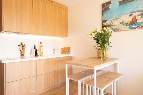 une cuisine avec des placards en bois et une table avec des fleurs dans l'établissement 10km St Tropez, Studio Cosy, à La Croix-Valmer