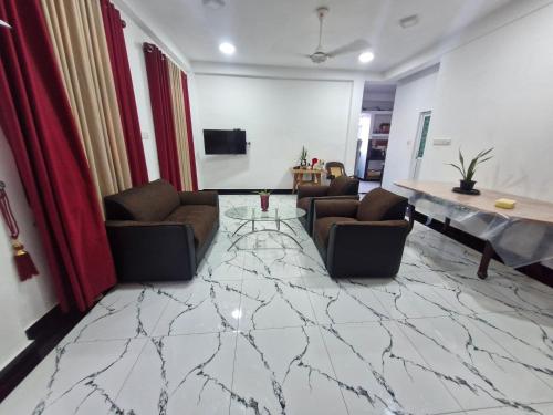 a living room with chairs and a table and a marble floor at TRINCO VISTARA GUEST House in Trincomalee