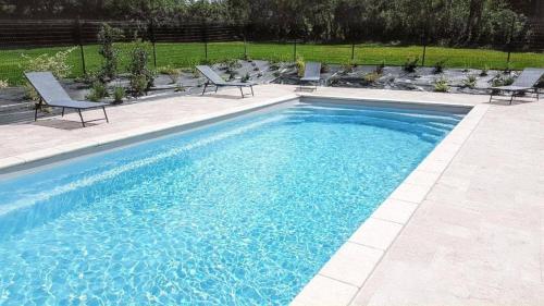 - une piscine avec 2 chaises dans l'établissement Le Pigeonnier - Piscine Privée et Jacuzzi, à Thénac