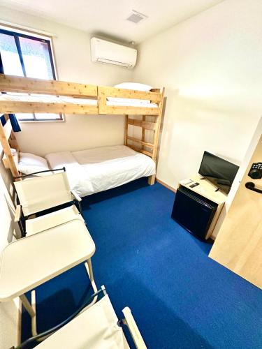 a room with two bunk beds and a desk and chairs at マリンハウス加賀 in Matsue