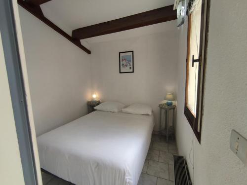 une chambre avec un lit blanc et une fenêtre dans l'établissement Appart 152, Port Soleil au village naturiste, au Cap d'Agde
