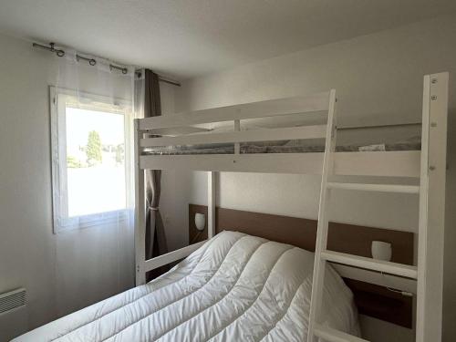 une chambre avec deux lits superposés et une fenêtre dans l'établissement Appartement climatisé, 2 pièces, piscine, terrasse, parking privé, proche port - Gruissan - FR-1-229-372, à Gruissan