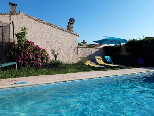 une piscine avec deux chaises et un parasol dans l'établissement Maison provençale avec une grande piscine, à Garons