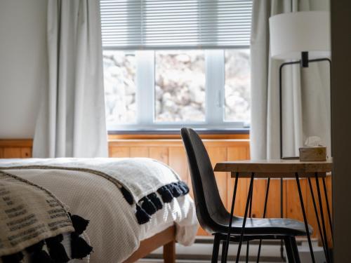 a bedroom with a bed and a chair and a window at Le Relais des Hautes Gorges in Saint Aime Des Lacs
