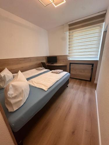 a bedroom with a bed and a desk and a window at Bach's Restaurant Bar Hotel in Erkrath