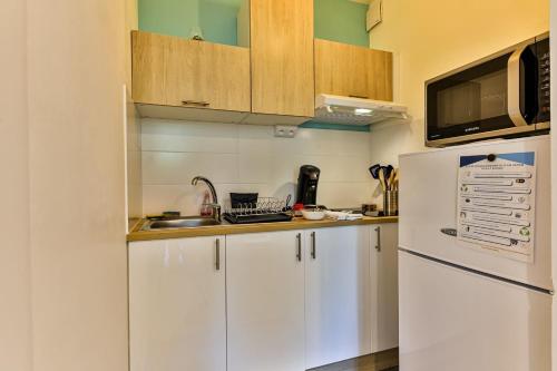  La cuisine est équipée de placards blancs et d'un réfrigérateur. dans l'établissement Un Air de Vacances - À 2 pas de la mer, à Saint-Hilaire-de-Riez