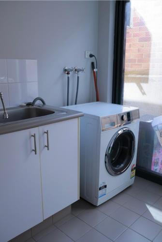 a washing machine in a kitchen next to a sink at Home Sweet Perth in Perth