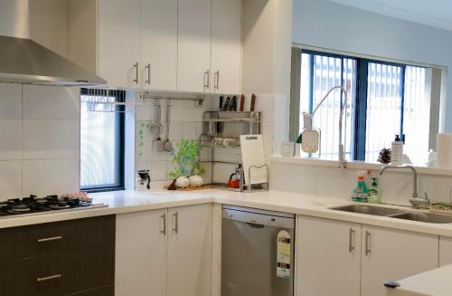 una cucina con mobili bianchi e un lavandino di Home Sweet Perth a Perth