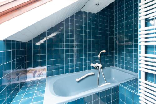 ein blau gefliestes Badezimmer mit Badewanne in der Unterkunft Cottage au Calme in Gèdre