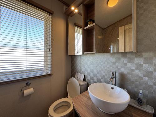 une salle de bain avec un lavabo, des toilettes et un miroir dans l'établissement Stewarts Resort Lodge 59, à St Andrews