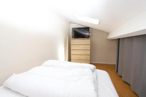 une chambre avec un lit blanc et une télévision dans l'établissement Petite maison avec terrasse en bord de plage, à Saint-Cyprien