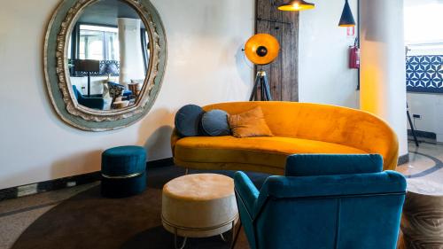 a living room with an orange couch and a mirror at Gardone Palace Hotel in Gardone Riviera